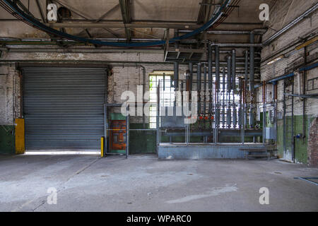 Old dirty room with the controller zone of pressure sensors, pump station and metal pipe system on ceiling and wall in factory or industrial building. Stock Photo