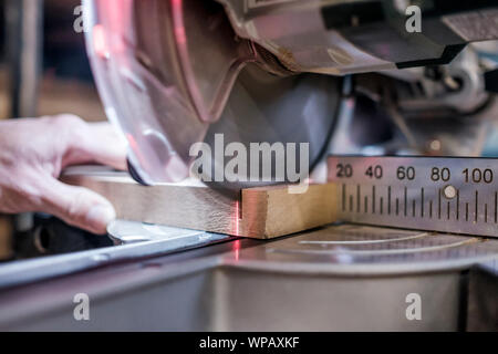 Man carpenter worker working driving circular saw to cut boards on a new furniture detail. Side view Stock Photo