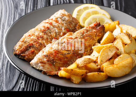 Grilled mackerel served with potato wedges and lemon closeup on a plate on the table. horizontal Stock Photo