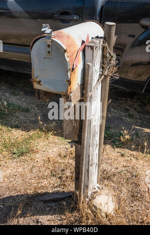 Beat-up mailbox, rusted and held up by wooden stake and rope in Santa Barbara County, California. Stock Photo