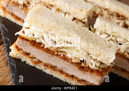 Japanese Katsu Sando sandwiches with tonkatsu sauce and cabbage close-up on a slate board on the table. horizontal Stock Photo