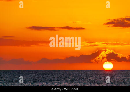 Beautiful large red sunset over the Pacific Ocean behind colorful clouds on Maui, Hawaii, USA Stock Photo