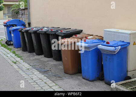 Various garbage cans stand on the street. Stock Photo