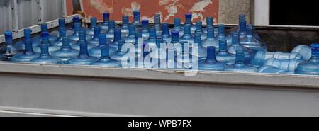 Many 5 gallon big water bottles stacked on back of truck. Stock Photo