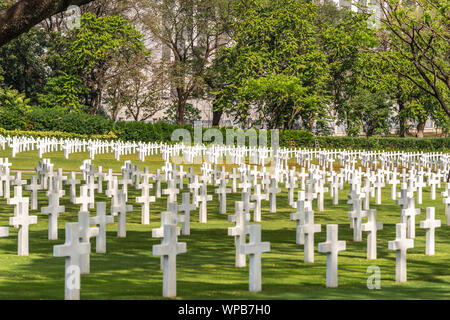 Manila, Philippines - March 5, 2019: American Cemetery and Memorial park. Closeup of Green field filled with rows of white crosses. Trees and bushes i Stock Photo