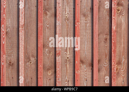 Background from old red faded planks with slats. Many hats from nails. Fence without gaps. Stock Photo