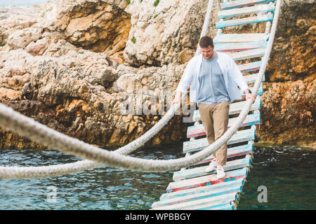 man walking by suspension bridge cross adriatic sea Stock Photo