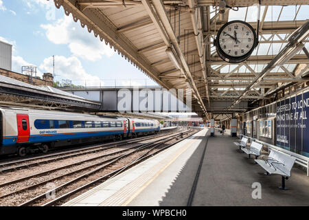 Almost empty railway station platform with old style clock, and train on other platform, Sheffield Railway Station, Sheffield, Yorkshire, England, UK Stock Photo