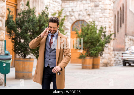 A handsome elegant man walking on the streets and talking on his phone a sunny day. Stock Photo