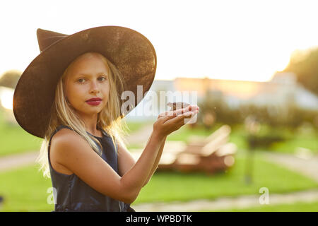 Waist up portrait of cute little witch holding frog while posing outdoors on Halloween, copy space Stock Photo