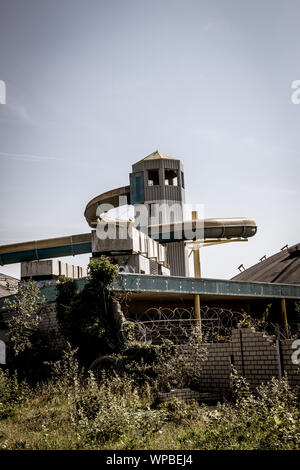 Outdoor shot of an old abandoned indoor swimming pool with its remarakable slide tower in Nes, island of Ameland, in August 2019 Stock Photo