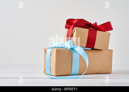 gift boxes in craft paper with blue and red ribbons on white background Stock Photo