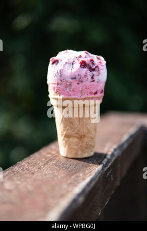 Waffle ice cream with cherry filling on a wooden table on a green background Stock Photo