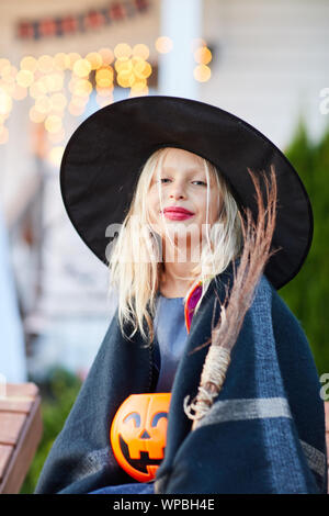 Portrait of smiling little girl wearing witch costume looking at camera on Halloween day, copy space Stock Photo