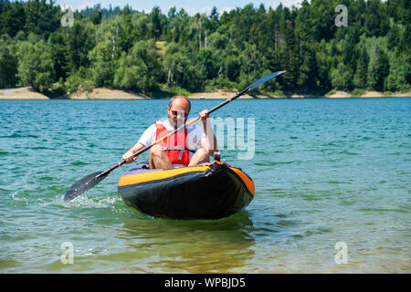 Man paddling in inflatable kayak on lake Lokve, in Gorski kotar, Croatia. Adventurous kayaking experience in a beautiful nature. Stock Photo