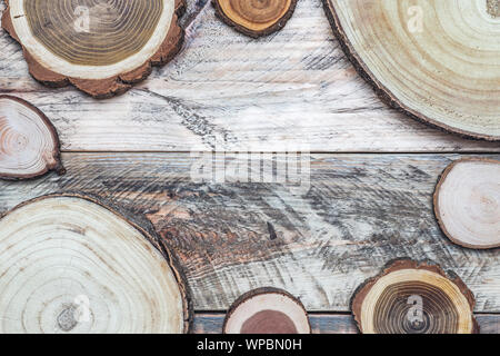 Tree logs slices top view on a weathered wooden background with copy space in the center. Stock Photo