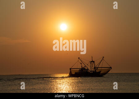 A fish trawler in the North Sea, Waddenzee at sunset on the island of Ameland Stock Photo