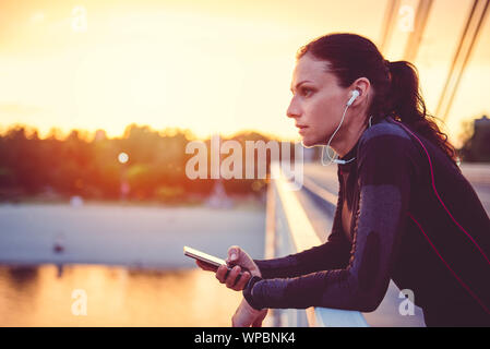 Fitness woman using smart phone and resting after running Stock Photo