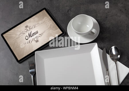 Tablet with stylish restaurant logo and laid table Stock Photo
