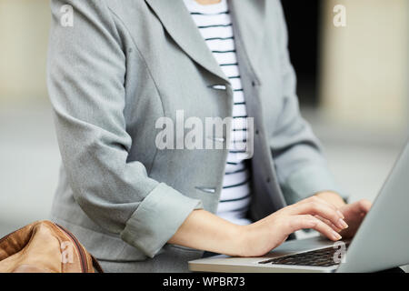 Mid section closeup of unrecognizable businesswoman typing on keyboard wile using laptop outdoors, copy space Stock Photo
