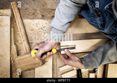 Carpenter using chisel cutting out groove in pine plank for furniture Stock Photo
