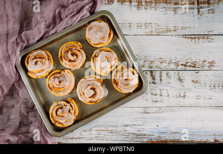 Sweet homemade cinnamon rolls in baking pan on white wooden table. Stock Photo