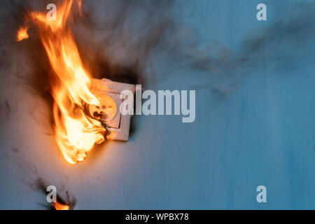 Apartment fire is caused by electrical outlet faults. Burnt and damaged electric plug socket from overload short circuit. Stock Photo