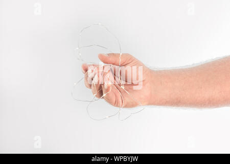 Hand entangled by a cable with many small lights on a white background and space to write. Stock Photo