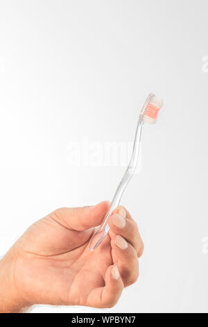 A hand holding a transparent plastic brush on a white background. Stock Photo
