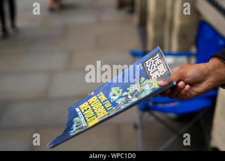 Vendor selling the Big Issue on the high-street in Wells, Somerset, UK. Using selective focus. Stock Photo