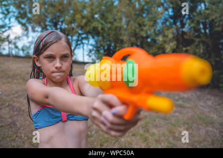 Little girl holding orange water gun Stock Photo
