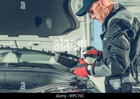 Auto Service Mechanic Checking Car Fuses Box Looking For Burned Fuse. Automotive Industry. Stock Photo