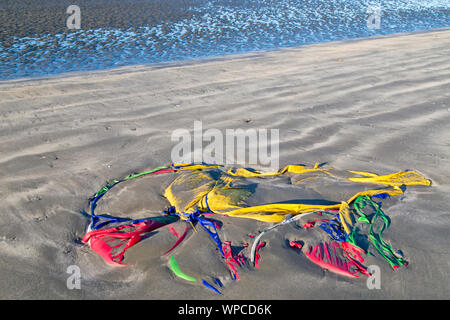 Low tide deposited colorful polyester tent along coastal beach. low tide. Stock Photo