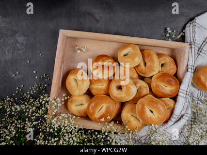 Homemade mini bagels on wooden tray with flowers. Stock Photo