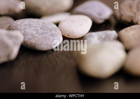 Scattered pebble stones on a dark background close up Stock Photo