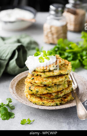 Zucchini quinoa fritters with sour cream. Vegetable pancakes ready for eating. Healthy vegetarian food Stock Photo