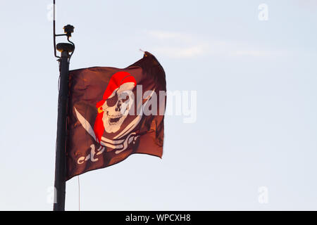 Pirate flag on ship over sky background. backlit. Stock Photo