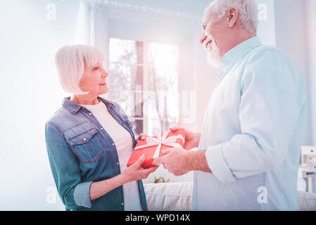 Caring loving mature husband making little surprise for his beautiful woman Stock Photo