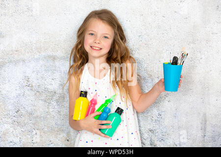 pretty blonde girl holds various colourful painting utensils in her hand Stock Photo