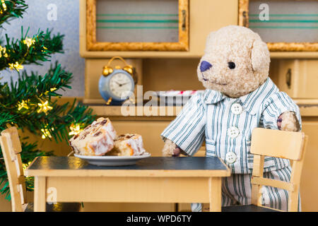 Little sweet tooth teddy bear visit kitchen at bedtime in nightwear pajama to eat delicious traditional german stollen christmas cake Stock Photo