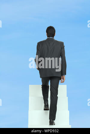 Rear view of a businessman walking up on staircase Stock Photo