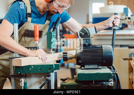 Carpenter making stairway drilling holes in stair rail Stock Photo