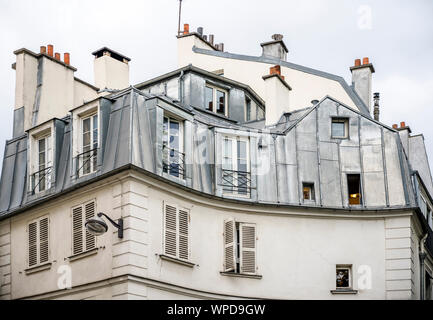 Rounded corner of residential apartments multi-storey house with wooden shutters and residential attic and balconies outside the windows located on on Stock Photo