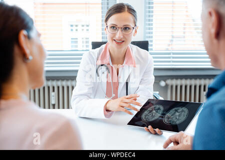 Doctor woman showing patients x-ray pictures on her tablet computer Stock Photo