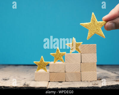 Businessman with a big golden star, rating or ranking system concept with wooden stairs Stock Photo