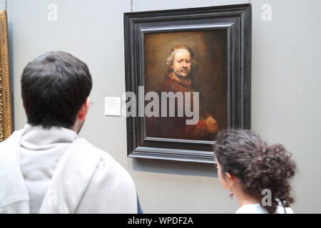 A young couple standing in front of the Self-portrait at the age of 63 by Dutch painter Rembrandt at the National Gallery, London, UK Stock Photo