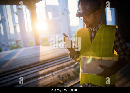 Male architect with blueprints using walkie-talkie Stock Photo