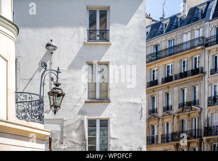 Corner of residential apartments multi-storey house with wooden shutters and residential attic and balconies outside the windows located on one of the Stock Photo