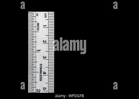 A used engineers steel ruler isolated against a black background Stock Photo