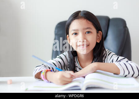 Smile little Asian girl doing homework with happiness for self learning and education concept select focus shallow depth of field Stock Photo